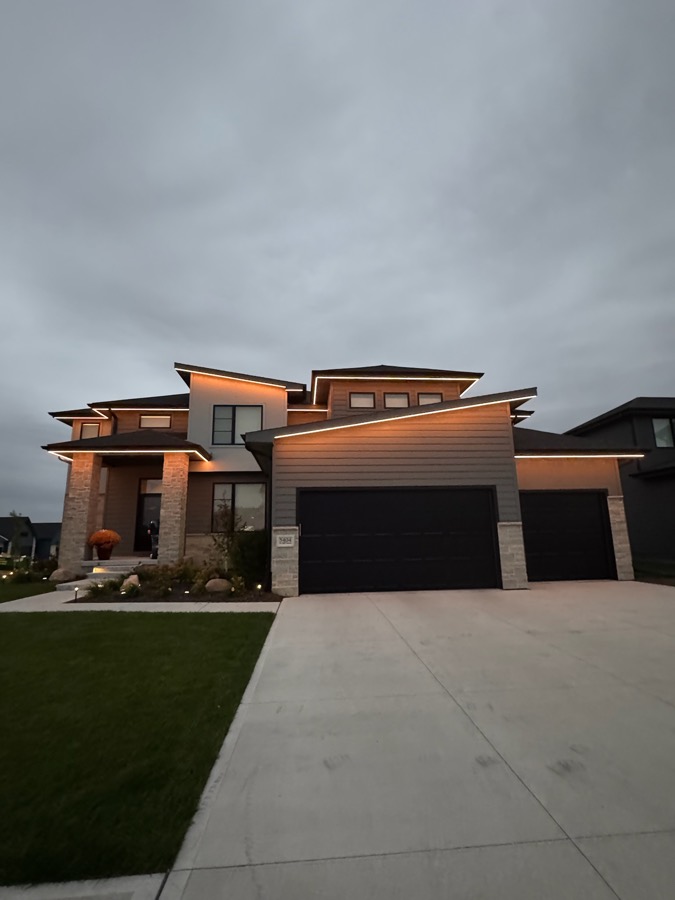 Two-story home with warm white roofline lighting at dusk