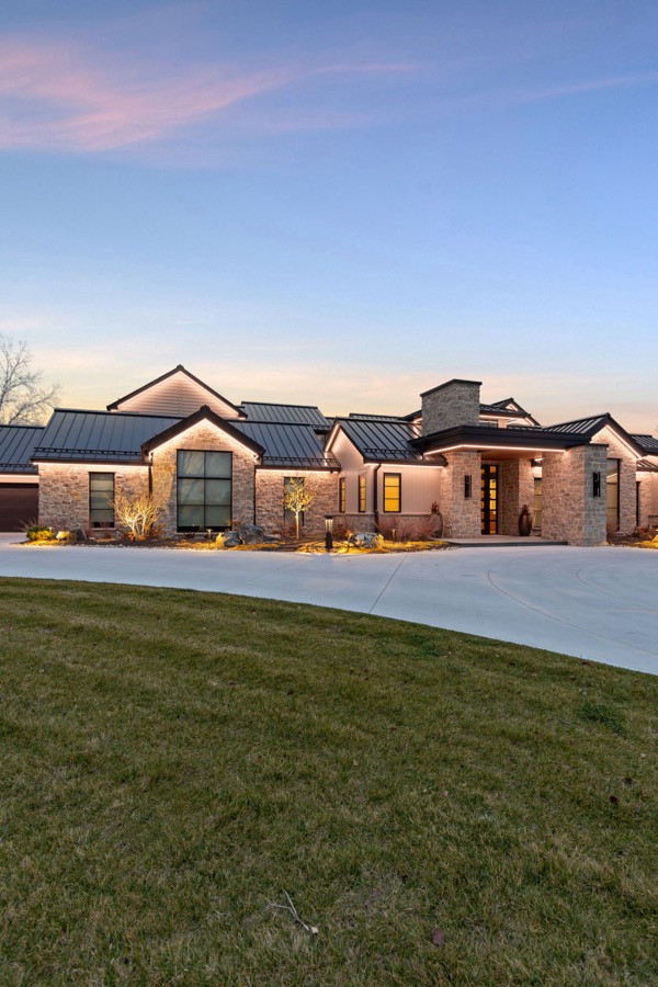 Sprawling stone home with roofline lighting at dusk